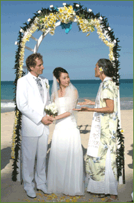 Couple under wedding arch with the minister